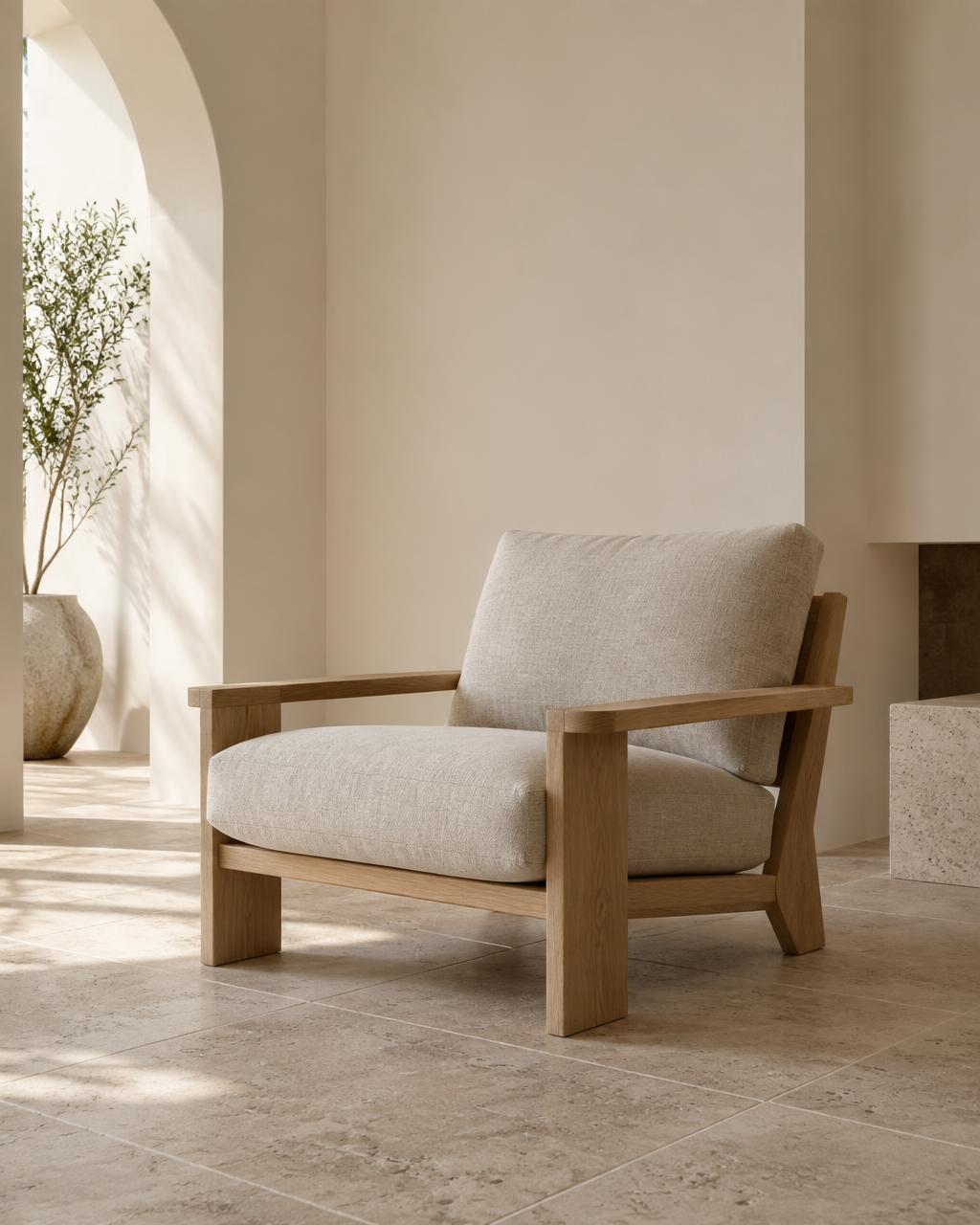 Oak-framed lounge chair with linen cushions beside a plaster archway